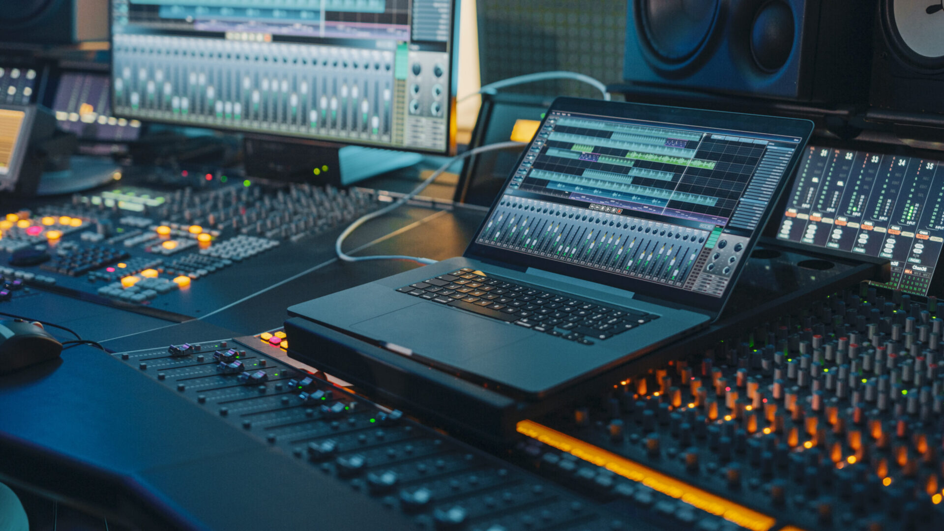 Modern Music Record Studio Control Desk with Laptop Screen Showing User Interface of Digital Audio Workstation Software. Equalizer, Mixer and Professional Equipment. Faders, Sliders. Record. Close-up